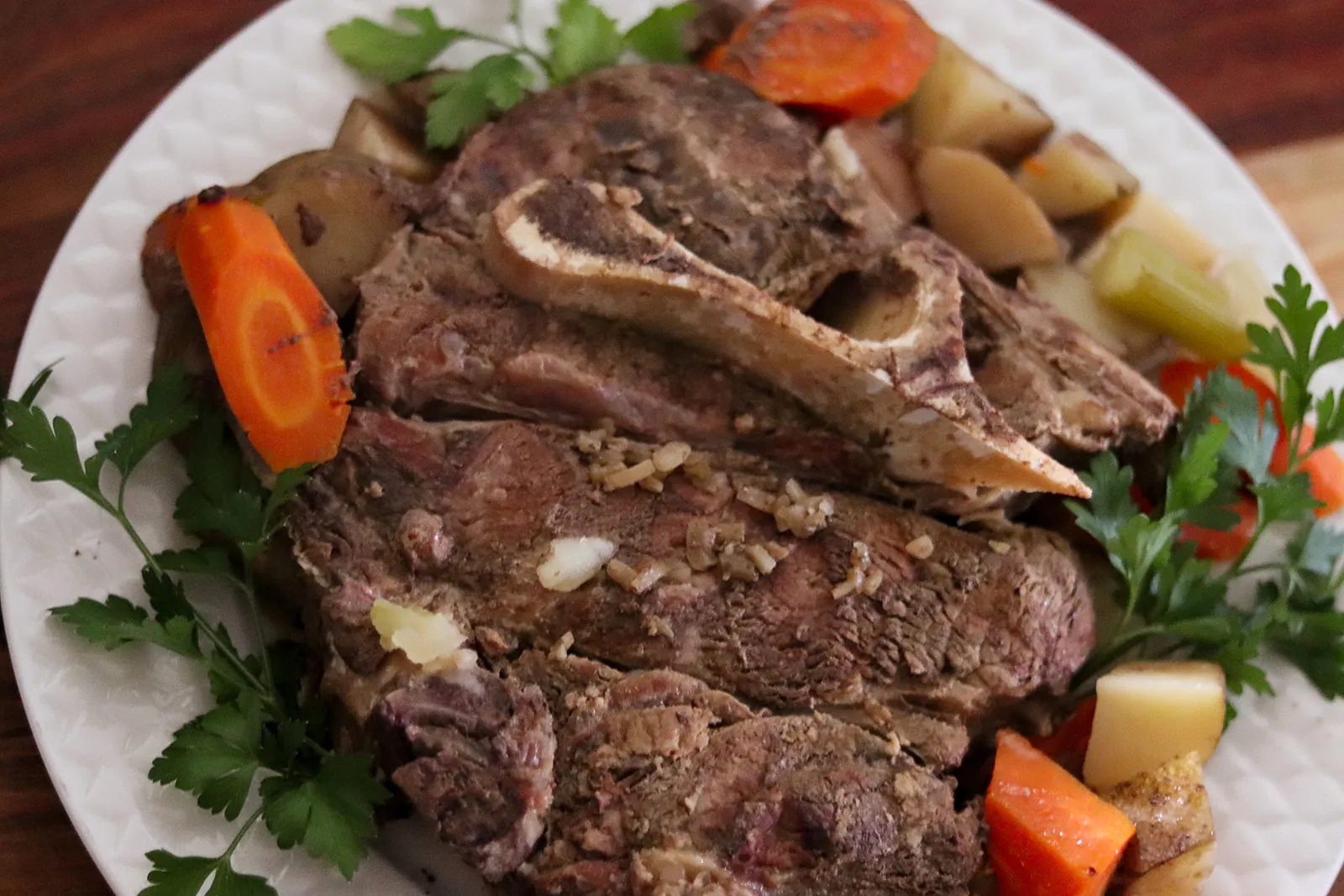 A Barton Beef roast with carrots and potatoes on a white plate